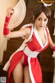 A woman in a red and white outfit holding a fan.