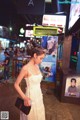 A woman in a white dress standing in the middle of a street.