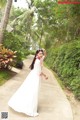 A woman in a white dress standing on a sidewalk.