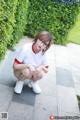 A woman wearing glasses and a white shirt crouching on the ground.