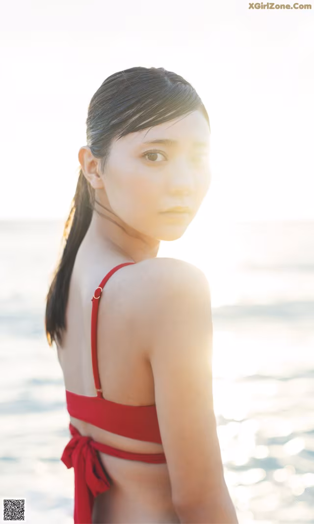 A woman in a red bikini standing on the beach.