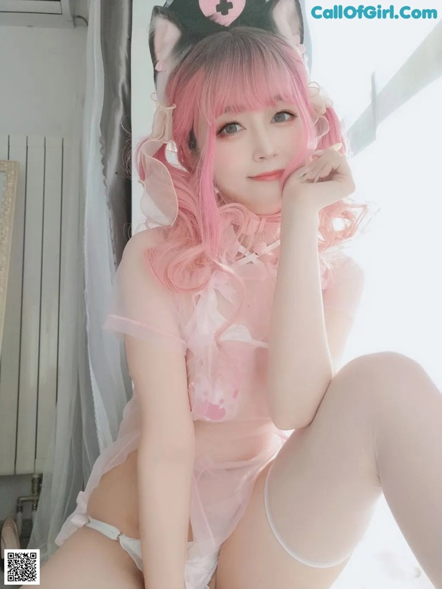 A woman in a pink nurse outfit is posing for a picture.