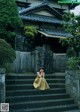 A woman in a yellow dress sitting on the steps of a building.