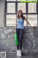 A woman standing in front of a window holding a green bag.