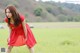 A woman in a red dress standing in a field.