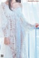 a woman wearing a white lace robe standing on a balcony