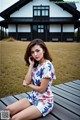 A woman sitting on a wooden bench talking on a cell phone.