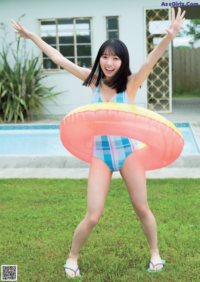 A woman in a bathing suit holding an inflatable ring.