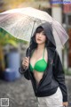 A woman in a green bikini holding an umbrella.