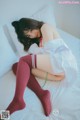 A woman laying on top of a bed wearing red stockings.