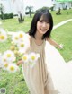 A woman in a beige dress holding a bunch of daisies.