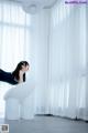 A woman sitting on top of a white chair in a room.