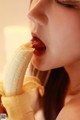 A woman is eating a banana with her mouth open.