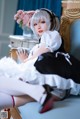 A woman in a maid outfit sitting on a chair.