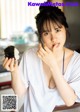 A woman sitting at a table eating a piece of sushi.