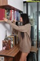 A woman standing in front of a bookshelf filled with books.