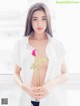 A woman in a white shirt holding a pink rose.