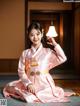 A woman in a pink hanbok sitting on the floor holding a lamp.