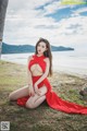 A woman in a red dress sitting on the ground.