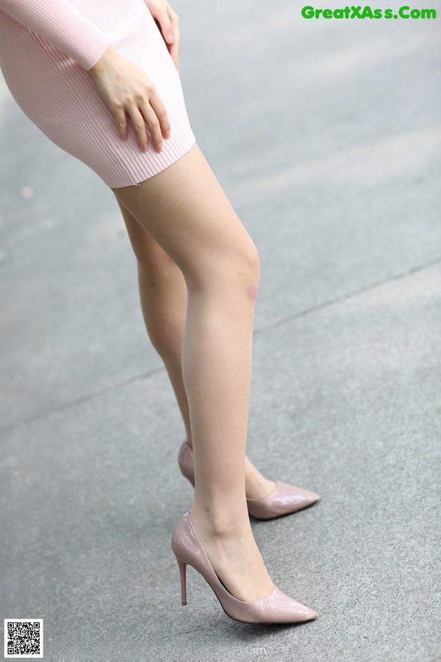 A woman in a pink dress and high heels is walking down the street.