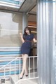 A woman in a blue dress standing on a balcony.