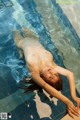 A woman in a white bodysuit floating in a pool.