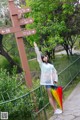 A woman standing next to a sign post holding an umbrella.