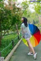 A woman walking down a path holding a colorful umbrella.