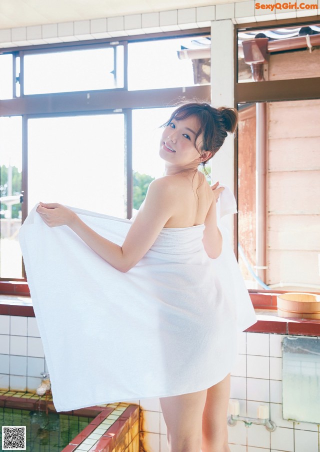 A woman in a white towel standing in a bathroom.