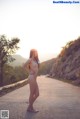 A naked woman standing on the side of a road.