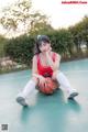 A woman sitting on a basketball court holding a ball.