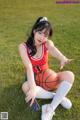 A woman sitting on the grass holding a basketball.