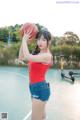 A woman holding a basketball on top of a basketball court.